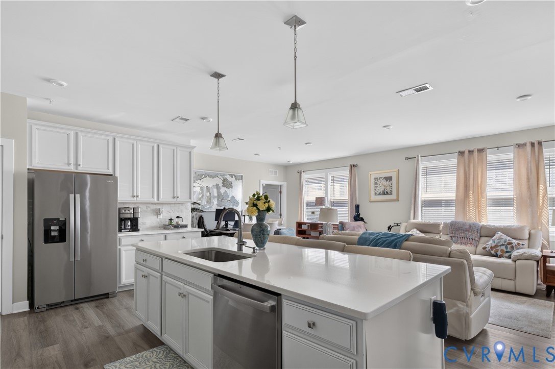 Kitchen featuring white cabinetry, a center island with a stone-surface countertop, stainless steel appliances, and wood-finish flooring