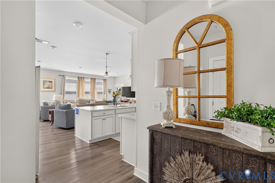 Wood-finish flooring, white cabinetry, and stone-surface kitchen island
