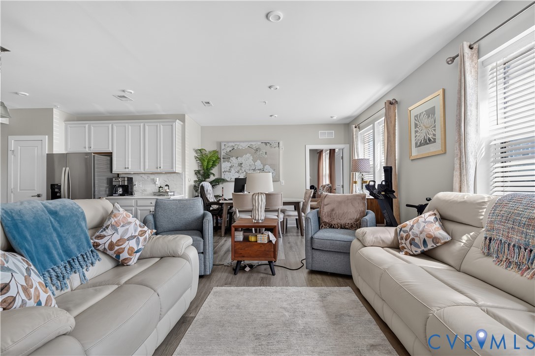 Open-concept living space featuring wood-finish flooring, recessed lighting, and white cabinetry