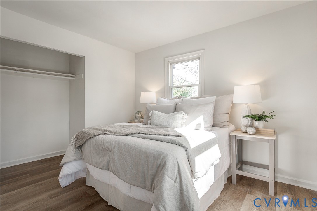 Neutral-toned walls, wood-finish flooring, and an inset closet featuring a built-in shelving rod