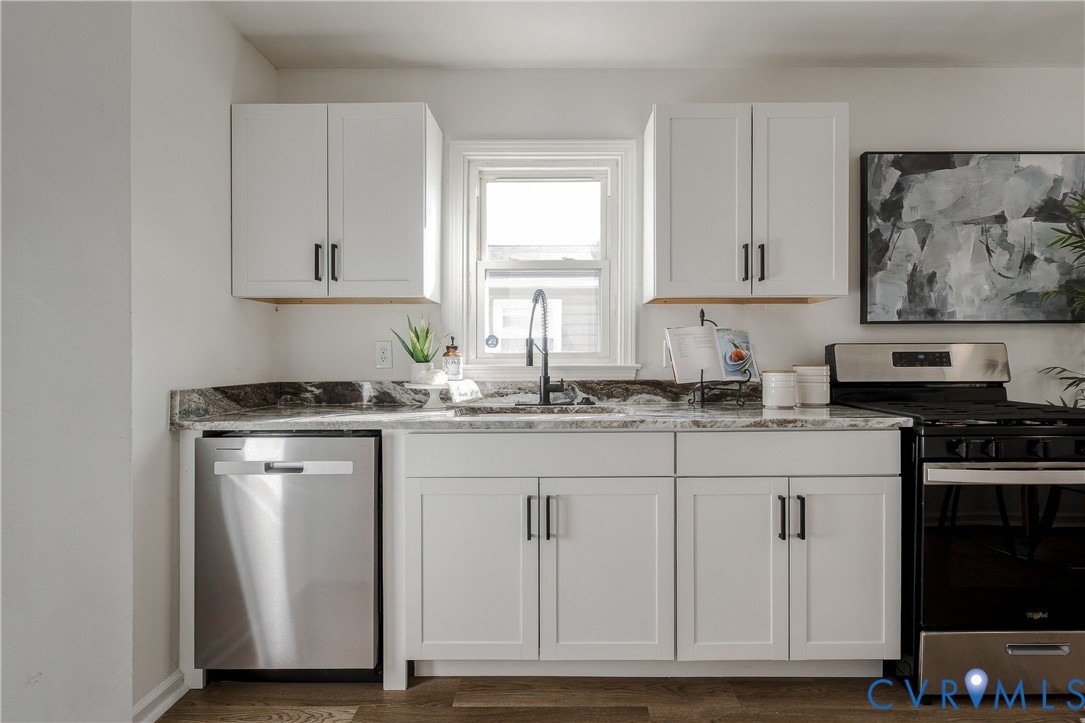 Kitchen featuring white shaker-style cabinetry, dark stone countertops, stainless steel dishwasher, high-arc matte black faucet, and wood-finish flooring