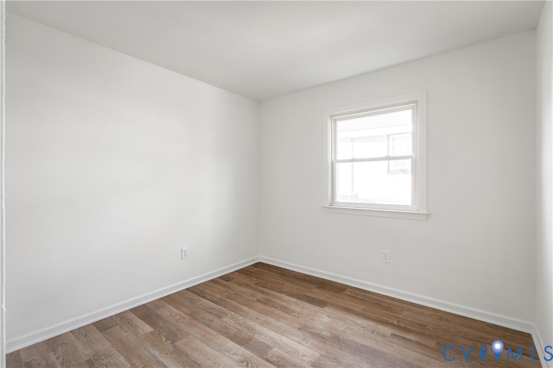 Neutral-toned room featuring wood-finish flooring, white walls, and a single-pane window with white trim