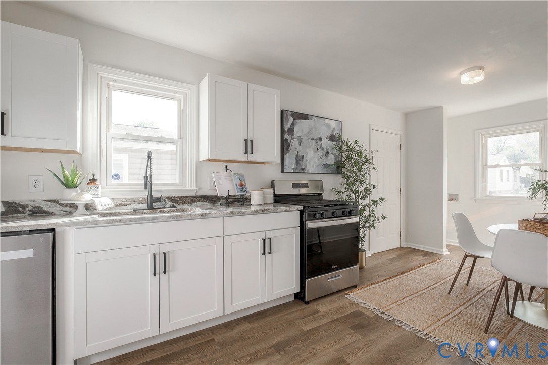 Kitchen featuring white shaker-style cabinetry, stone-finish countertops, matte black hardware, a high-arc faucet, and stainless steel range