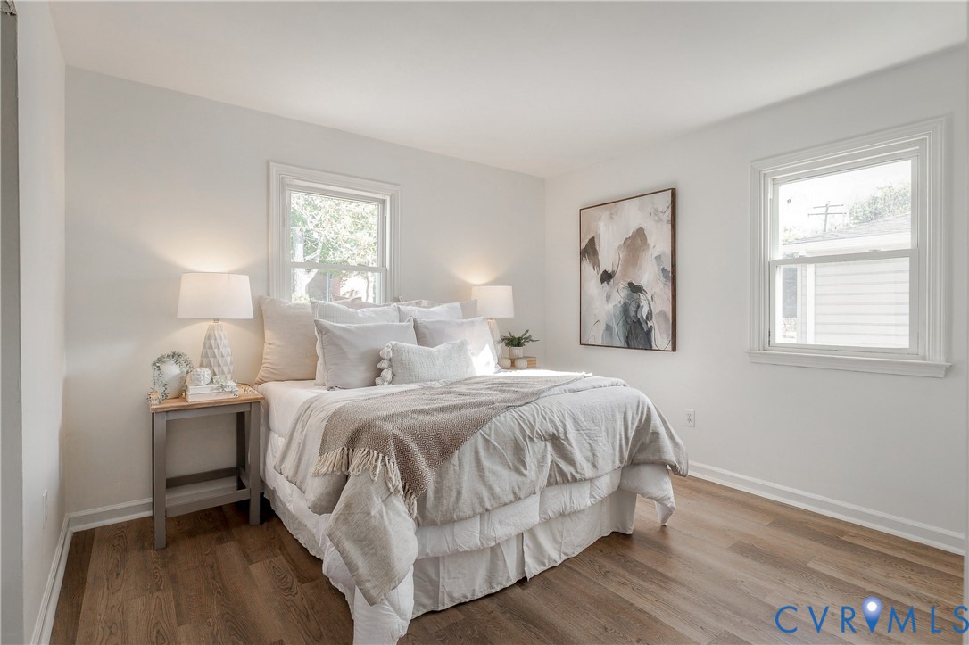 Neutral interior featuring wood-finish flooring, two double-hung windows, and crisp white wall finishes