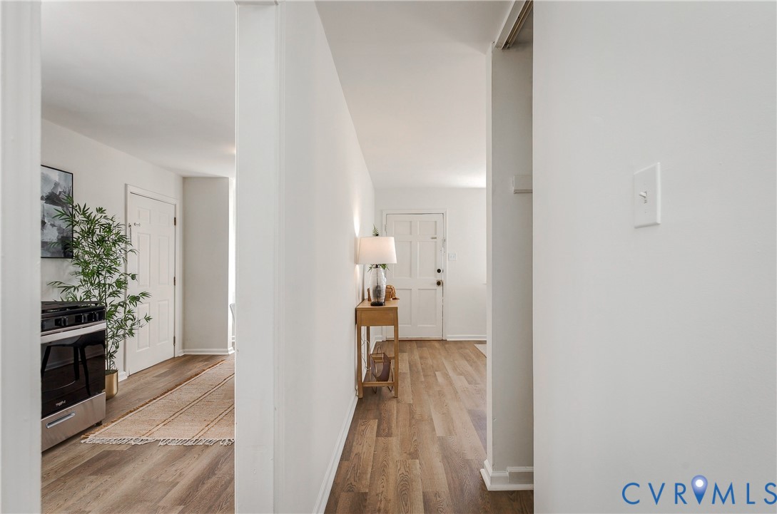Interior hallway featuring wood-finish flooring, white walls, and a six-panel exterior entry door