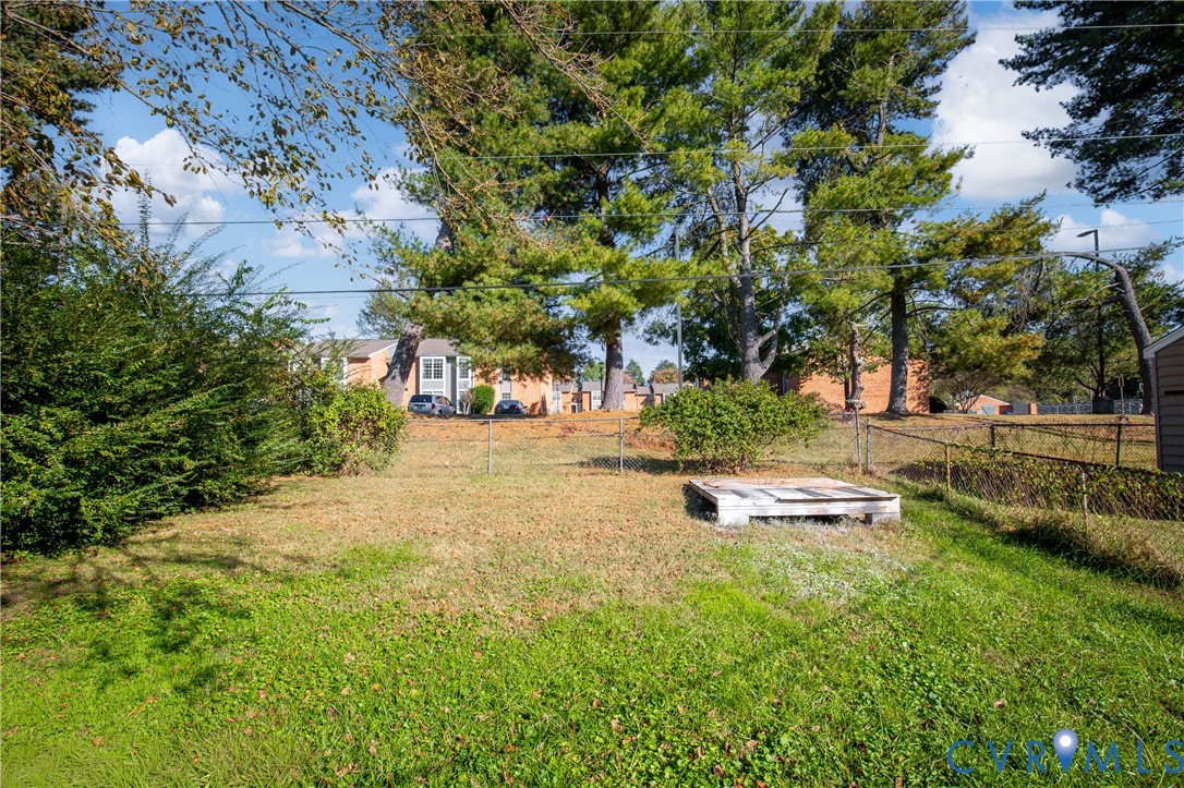 Backyard area featuring mature trees, perimeter chain-link fencing, and a concrete pad