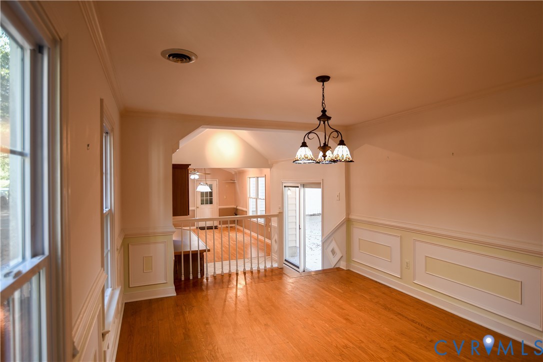 Hardwood flooring, decorative wall molding, and a multi-light chandelier