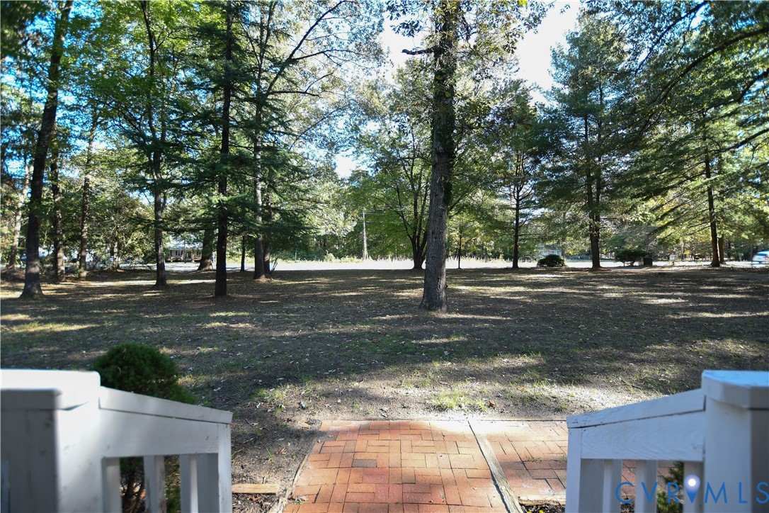 Spacious grounds featuring mature trees and a red brick walkway with white railings