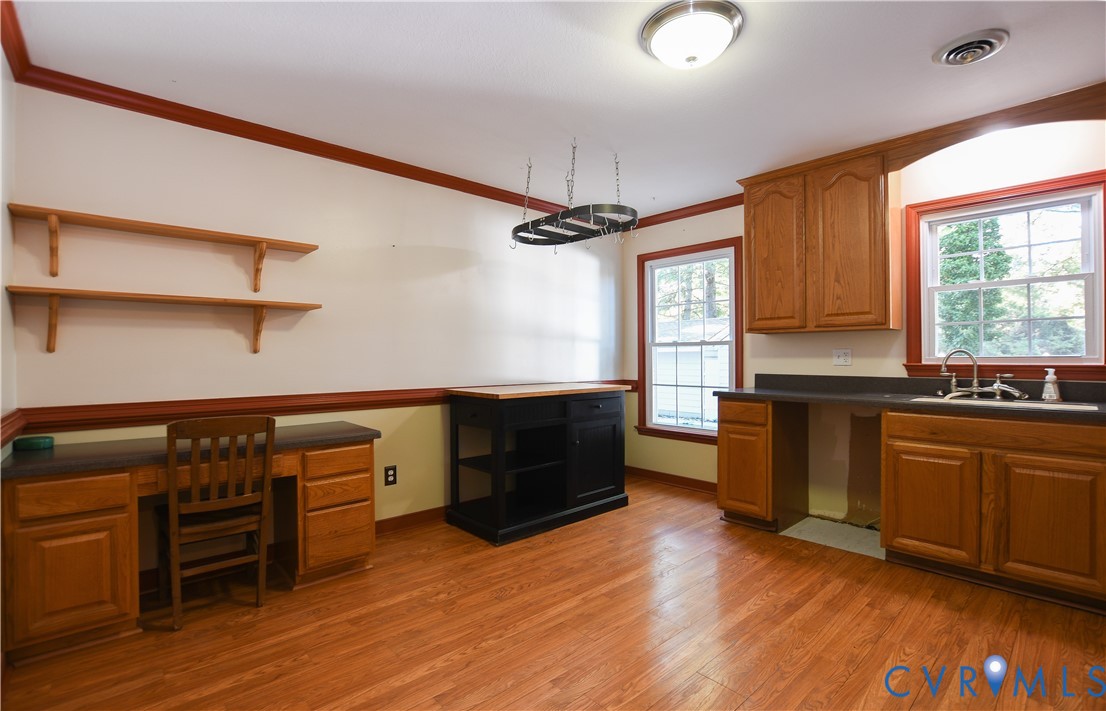 Wood-finish flooring, built-in wooden cabinetry, wall-mounted shelving, dual-window exposure, and integrated workstation