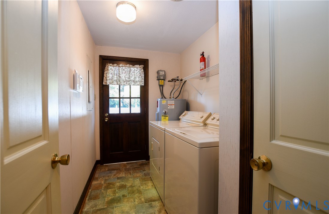 Laundry area featuring multi-tonal tile flooring, a glass-paneled exterior door, and a wall-mounted wire storage shelf