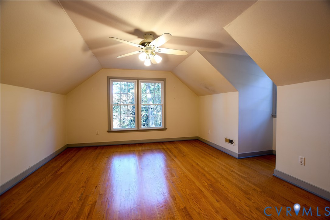 Room with vaulted ceilings, wood-finish flooring, and a multi-light ceiling fan