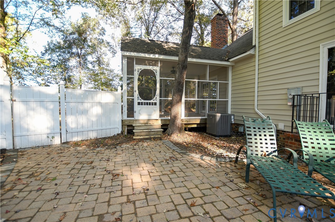 Screened porch featuring a decorative door, paver patio, and white vinyl perimeter fencing