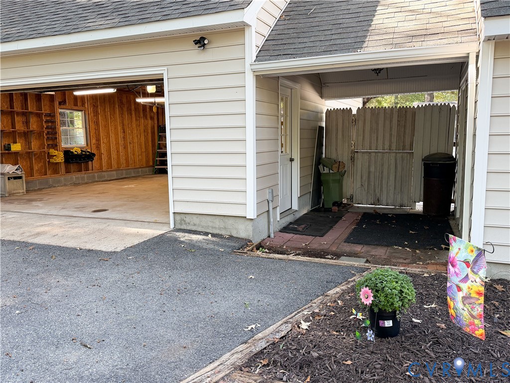 Exterior featuring horizontal vinyl siding, multi-car garage with built-in wall shelving, covered side entry, and enclosed side yard with privacy fencing