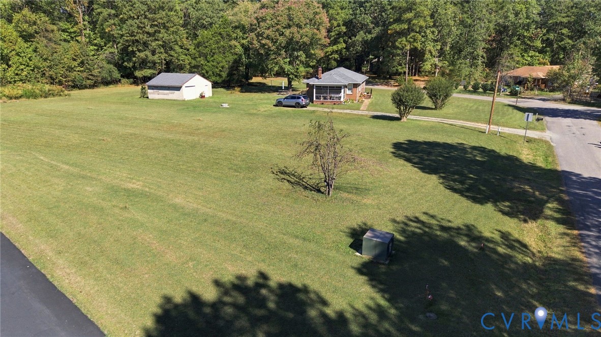 Expansive lawn, detached storage structure, and mature trees situated on a parcel with road frontage
