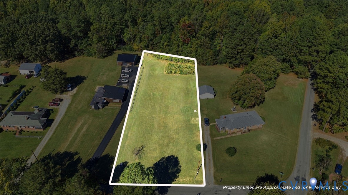 Expansive parcel of land featuring open grassy terrain, mature tree borders, and direct road access
