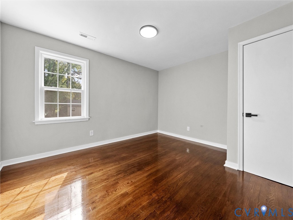 Refinished wood-finish flooring, neutral wall tones, multi-pane window with custom trim, and modern interior door with matte black hardware