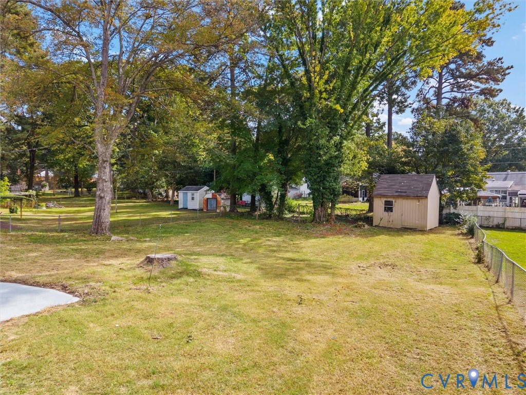 Expansive backyard featuring mature trees, a fenced perimeter, and two detached storage structures
