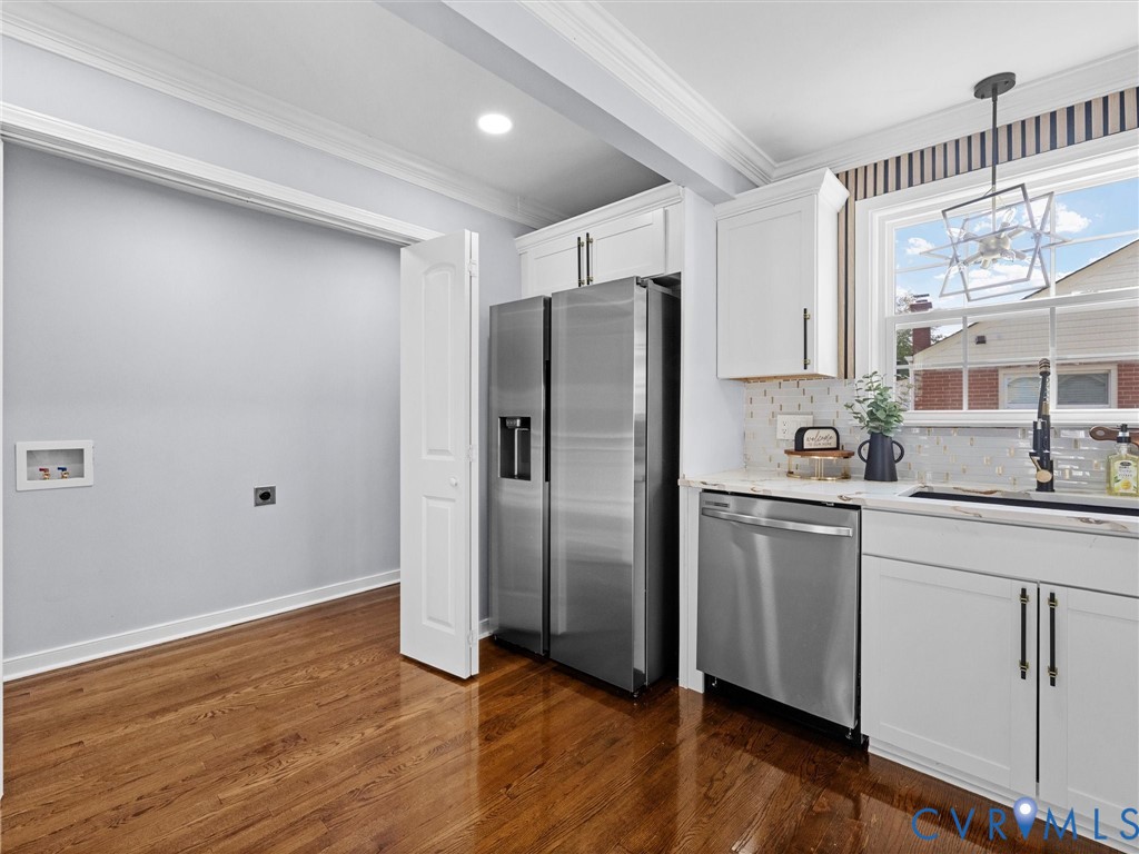 Kitchen featuring white Shaker-style cabinetry, stainless steel appliances, wood-finish flooring, stone-finish countertops, and crown molding