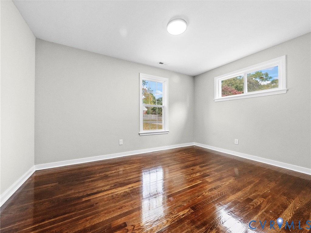 Neutral wall tones, polished wood-finish flooring, and multiple windows providing natural light