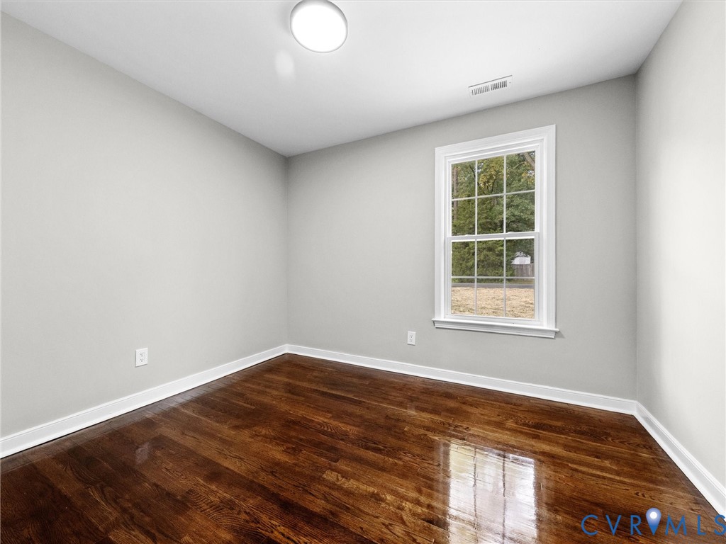 Interior space featuring wood-finish flooring, a double-hung window with casing, and a flush-mount ceiling light fixture