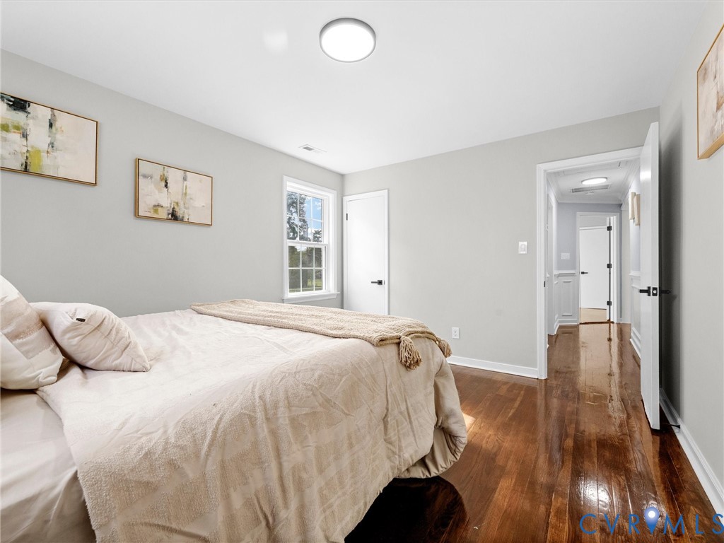 Wood-finish flooring, neutral wall tones, multi-pane window, and flush-mount lighting