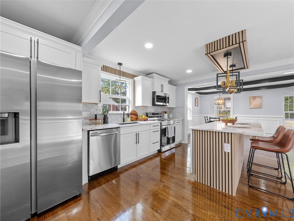 Kitchen featuring white shaker cabinetry, stainless steel appliances, a center island with wood slat detailing, recessed lighting, and wood-finish flooring