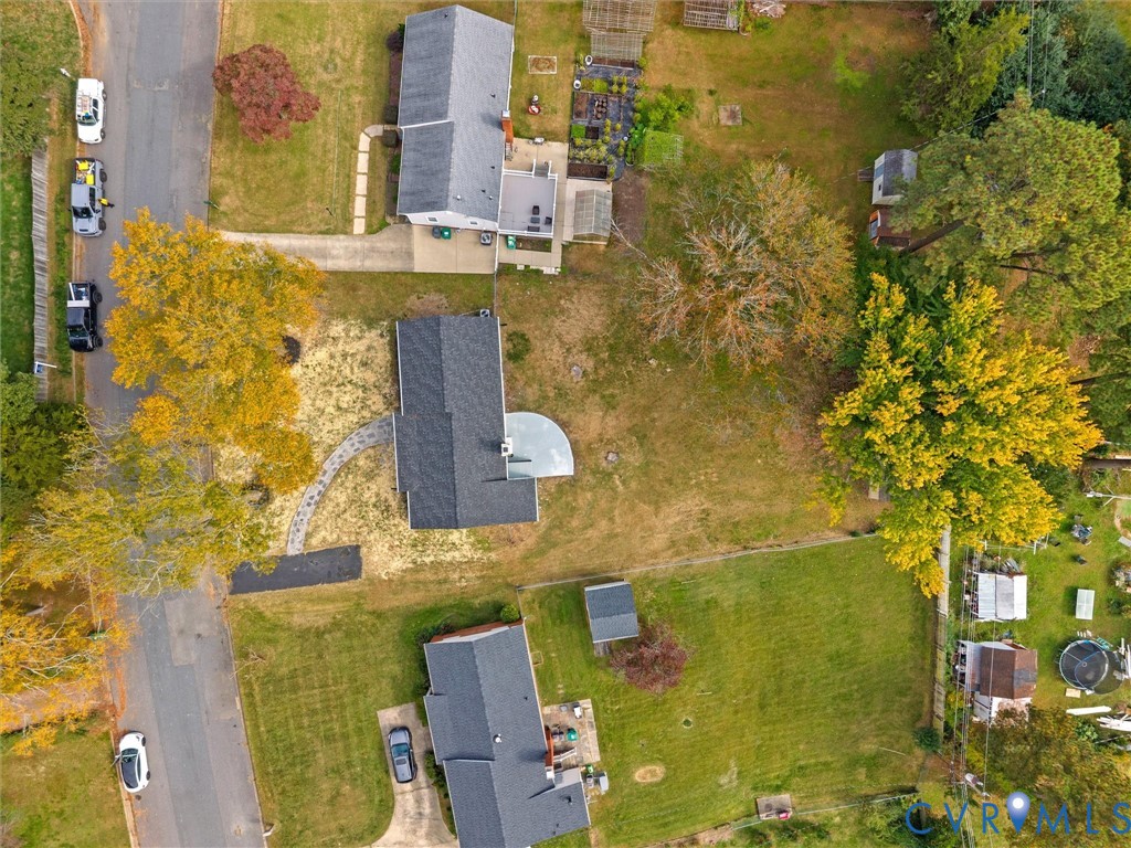 Aerial perspective of residential lot featuring mature trees, a curved stone paver walkway, and a rear patio