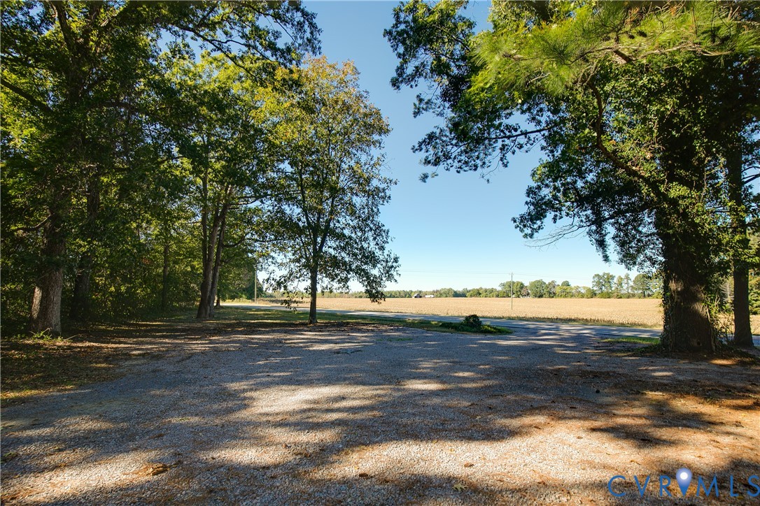 Expansive acreage featuring a gravel surface, mature timber, and open fields