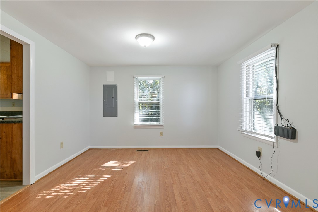 Interior space featuring wood-finish flooring, two windows with horizontal blinds, and a central ceiling-mounted light fixture
