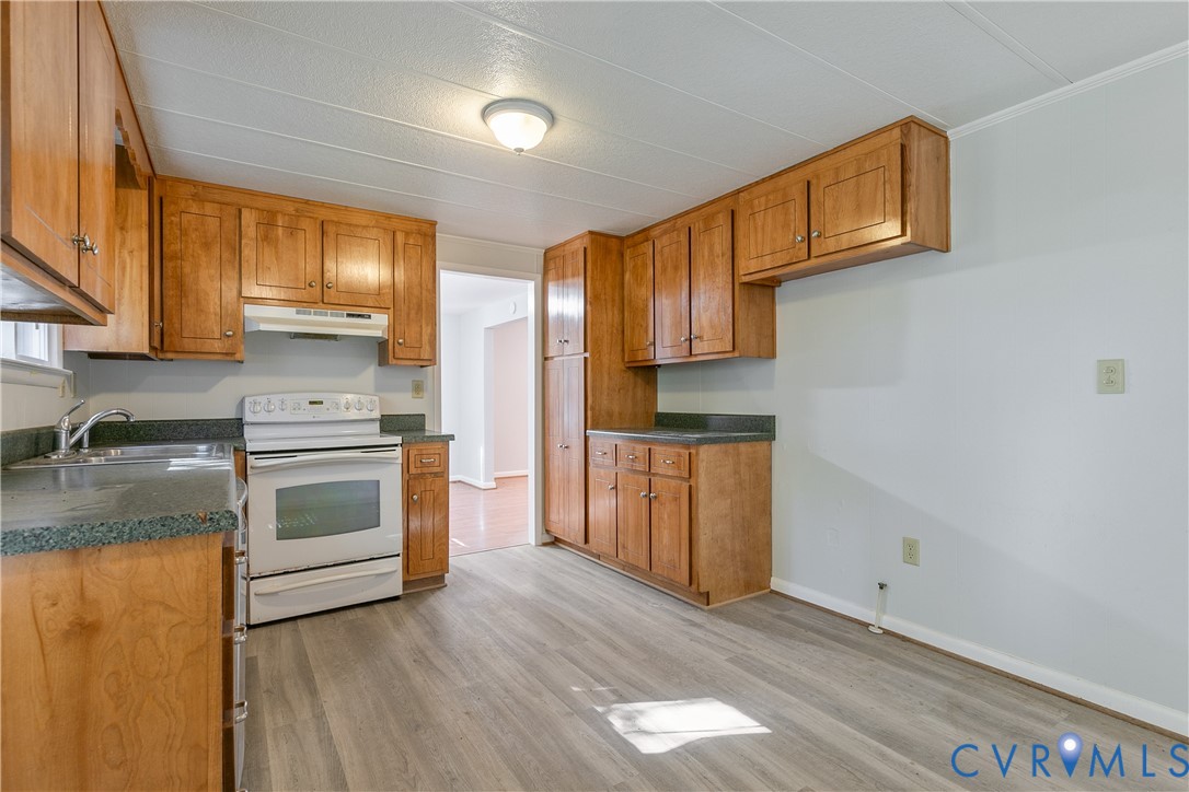 Kitchen featuring wood cabinetry, solid-surface countertops, wood-finish flooring, white range, and a ceiling-mounted light fixture
