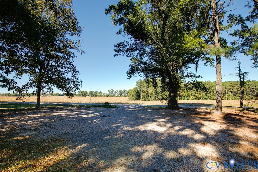 Expansive cleared lot featuring gravel ground cover, mature hardwood trees, and open terrain