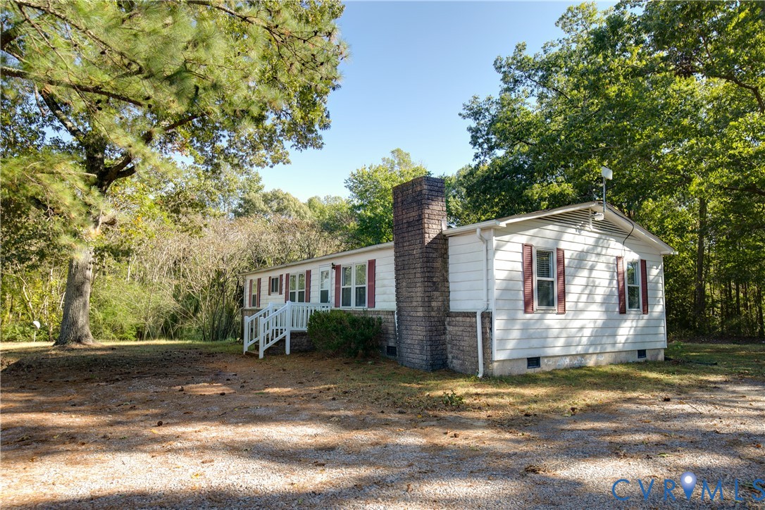 Single-story residence featuring white siding, red shutters, a brick chimney, and a raised wooden entryway Single-story residence featuring white siding, red shutters, a brick chimney, and a raised wooden entryway