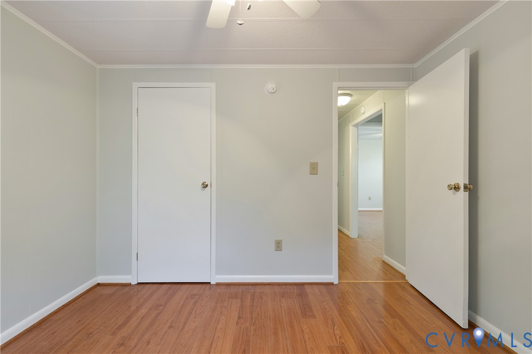 Neutral-toned interior space featuring wood-finish flooring, solid-core doors, and a ceiling-mounted fan