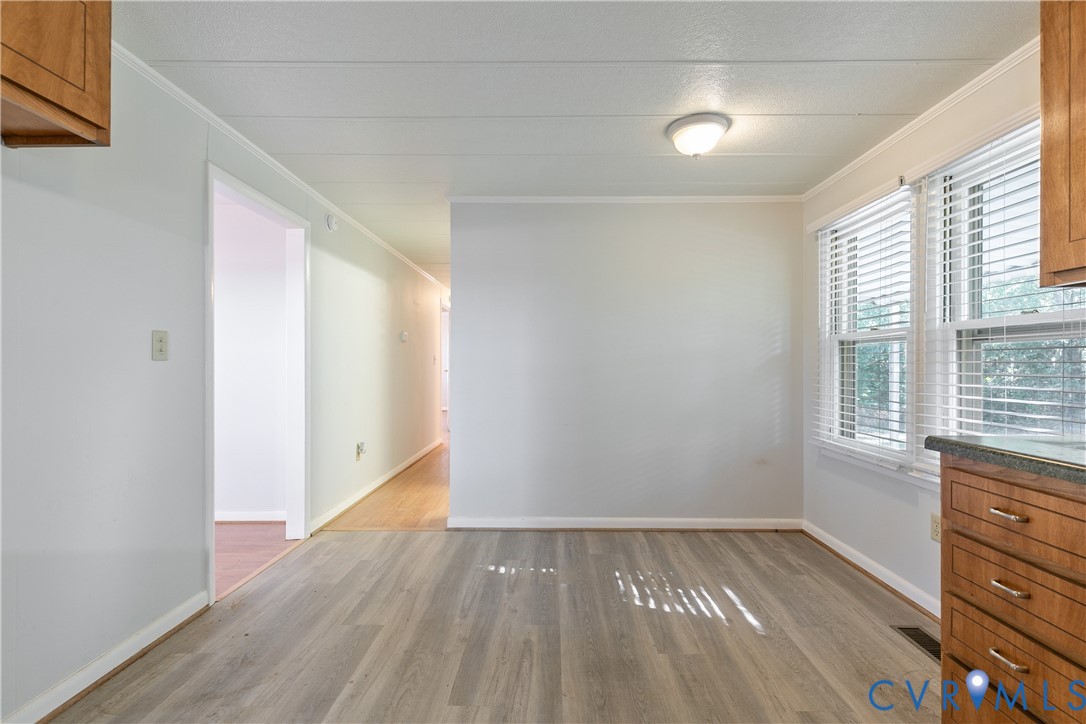 Wood-finish flooring, light-toned walls, flush-mount ceiling lighting, and double-window configuration with horizontal blinds