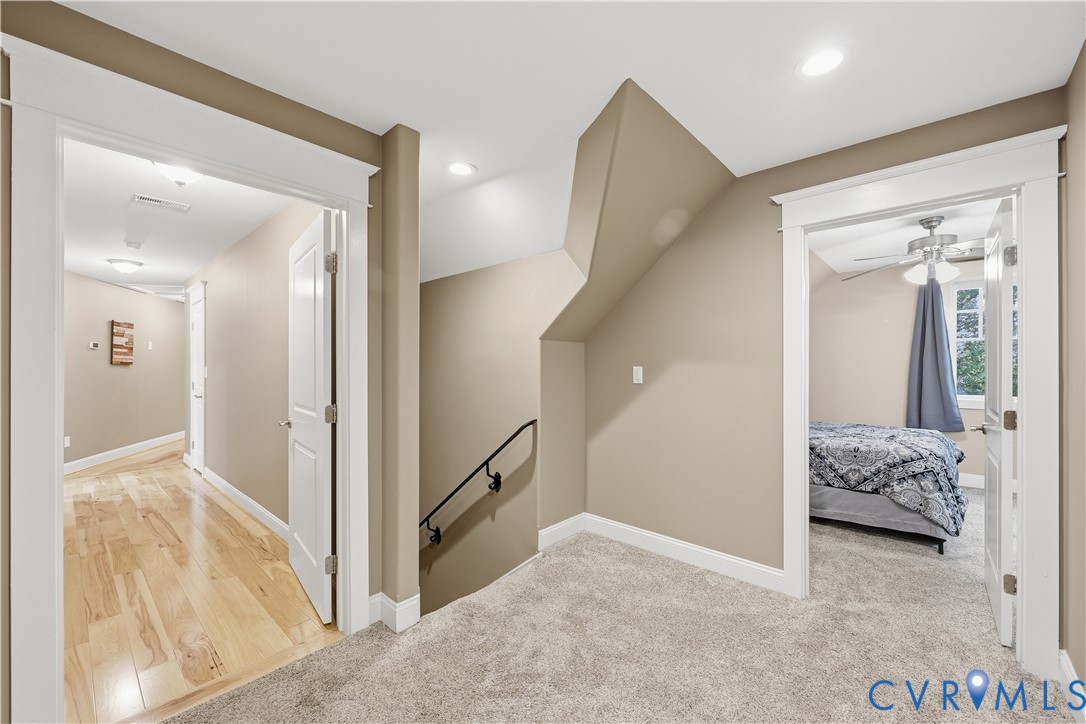 Hallway featuring neutral wall tones, recessed lighting, wood-finish flooring, carpeted floor surfaces, and decorative door casing