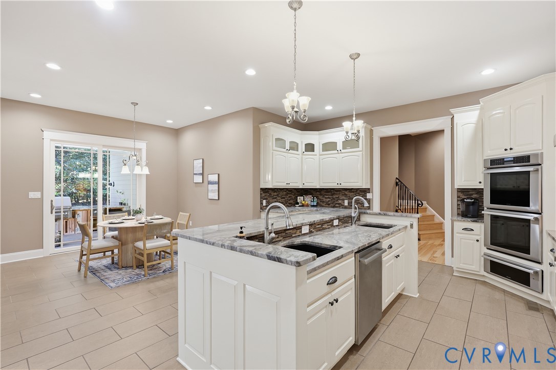 Kitchen featuring a stone-surface island, stainless steel double wall ovens, white shaker-style cabinetry, recessed lighting, and tile flooring
