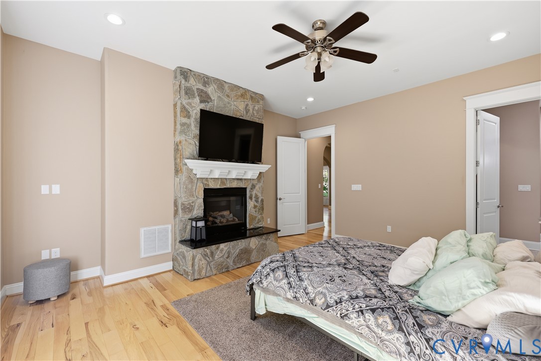 Primary Bedroom 2. Fireplace featuring floor-to-ceiling stone surround, decorative white mantle, and hearth with polished dark stone top