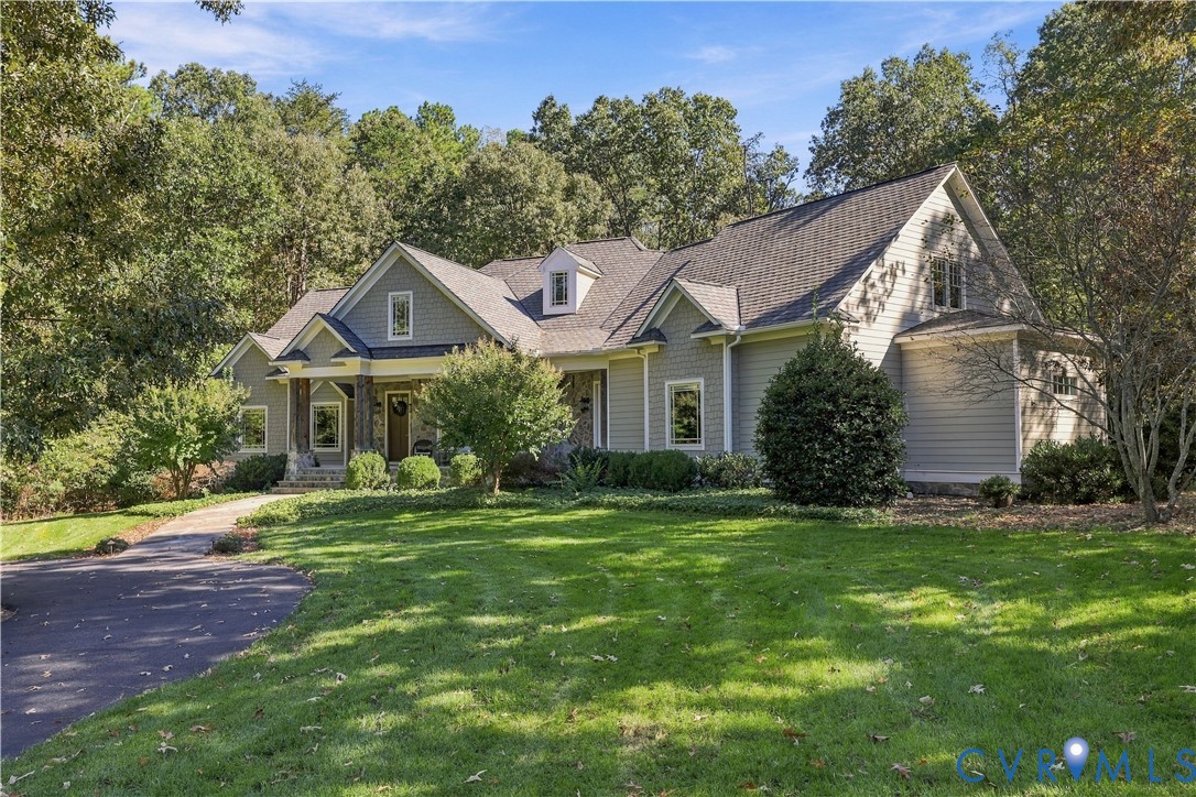 Multi-gabled exterior featuring horizontal lap siding, stone accent pillars, a covered entryway, and asphalt shingle roofing