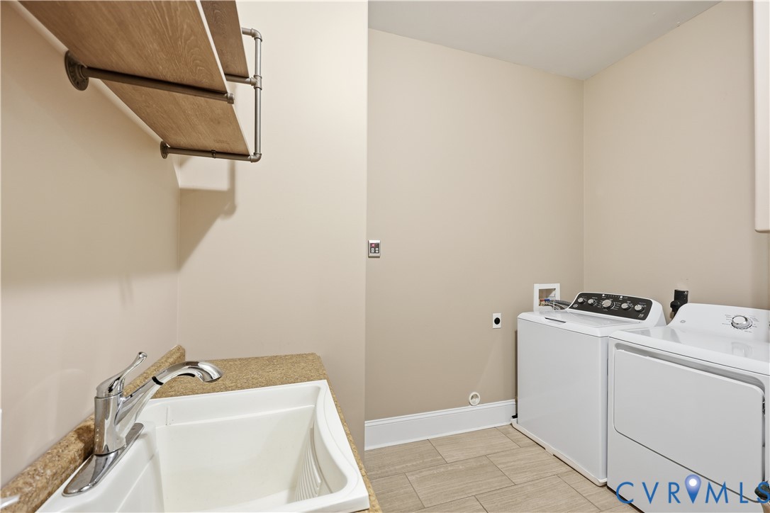 1st Floor Laundry area featuring tile flooring, a drop-in utility sink with stone-finish countertop, polished chrome faucet, and industrial-style pipe-supported shelving