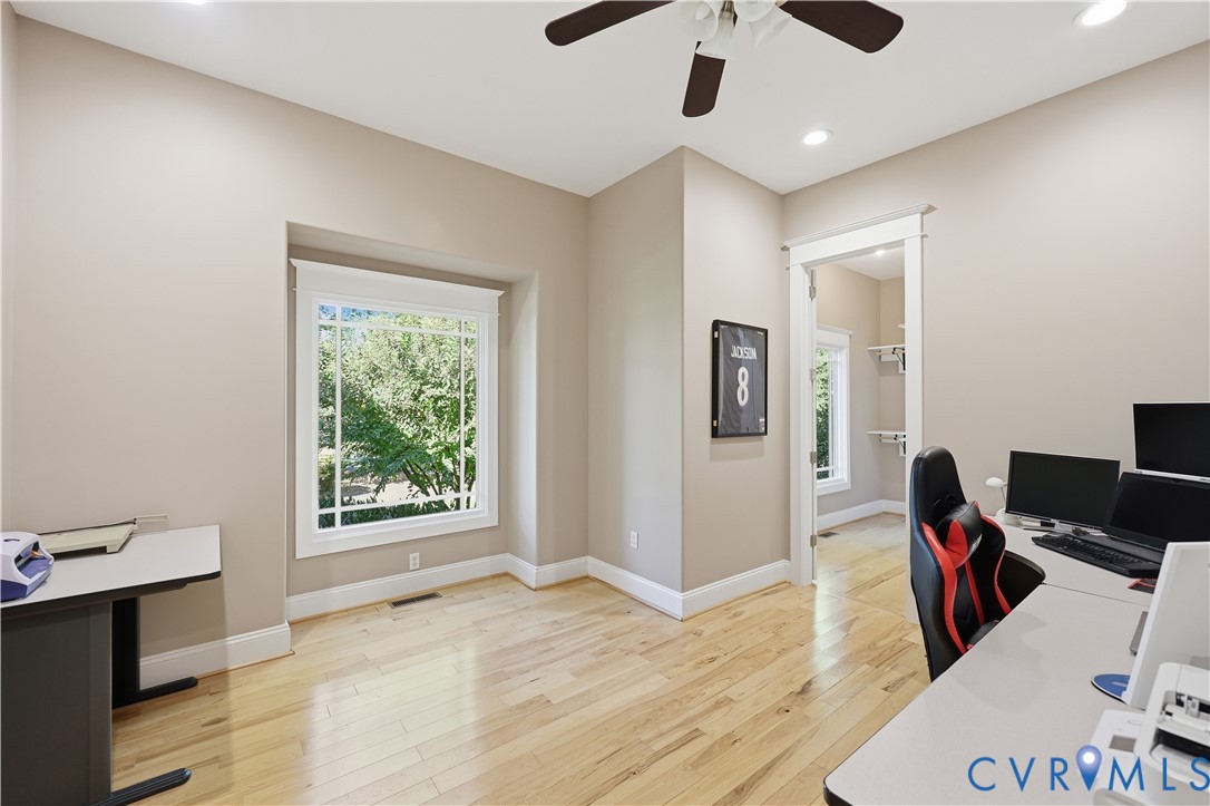 Wood-finish flooring, recessed lighting, ceiling fan, and large multi-pane window with substantial trim