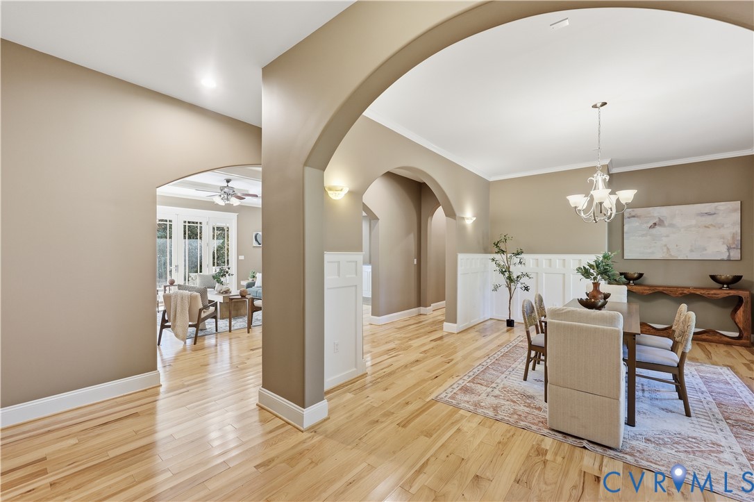 Interior featuring arched architectural pass-throughs, wood-finish flooring, wainscoting, recessed lighting, and a multi-arm chandelier