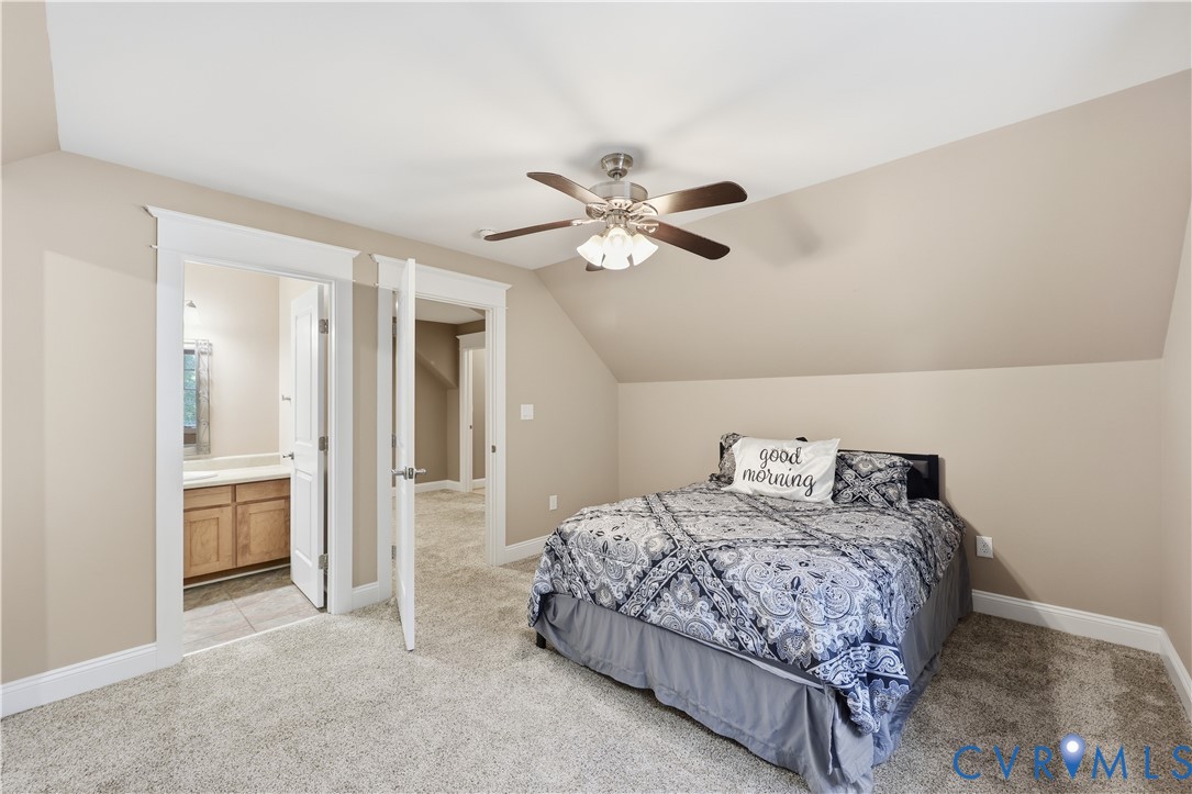 Upstairs Bedroom. Neutral-toned bedroom featuring vaulted ceilings, wall-to-wall carpeting, and a multi-blade ceiling fan with integrated lighting