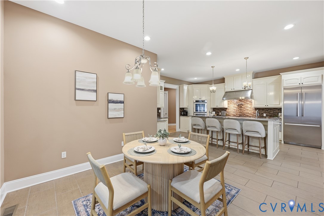 Kitchen featuring custom cabinetry, stainless steel appliances, tiled backsplash, center island with breakfast bar seating, and ceramic tile flooring