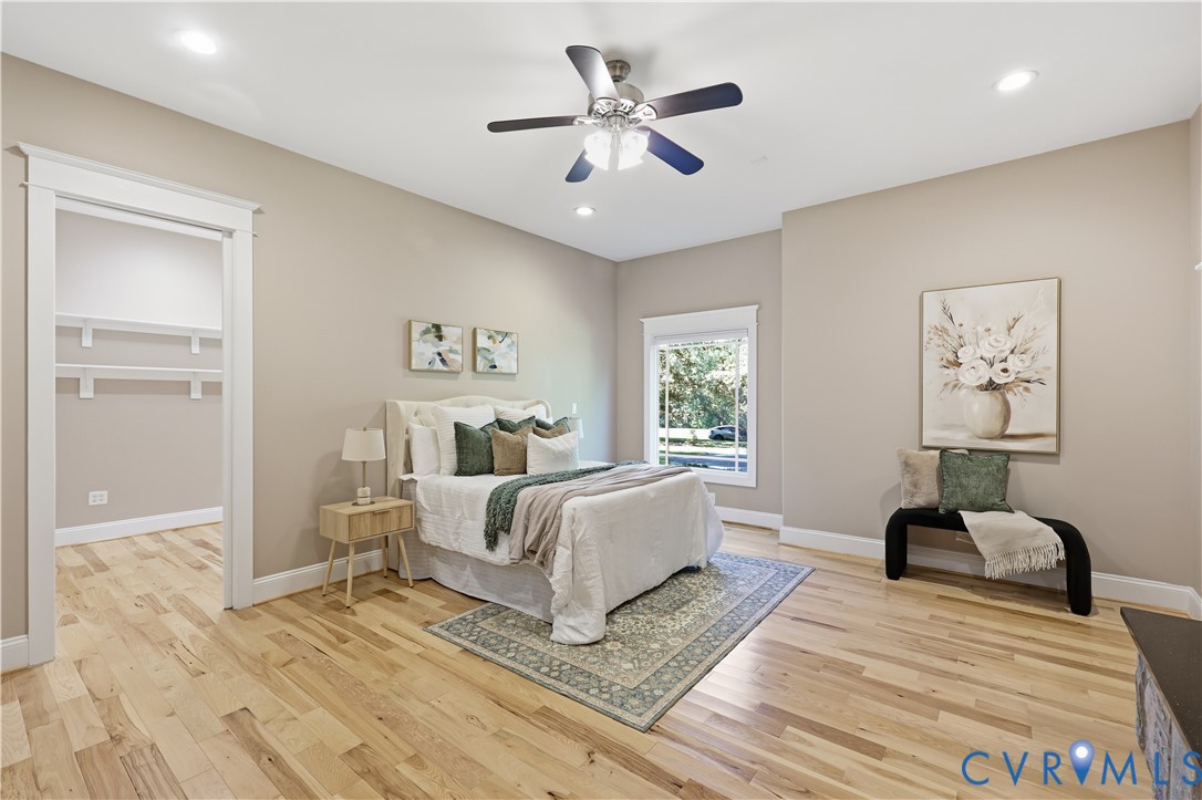 Spacious room featuring wood-finish flooring, recessed lighting, a ceiling fan with integrated light fixture, window with wide casing, and built-in closet shelving