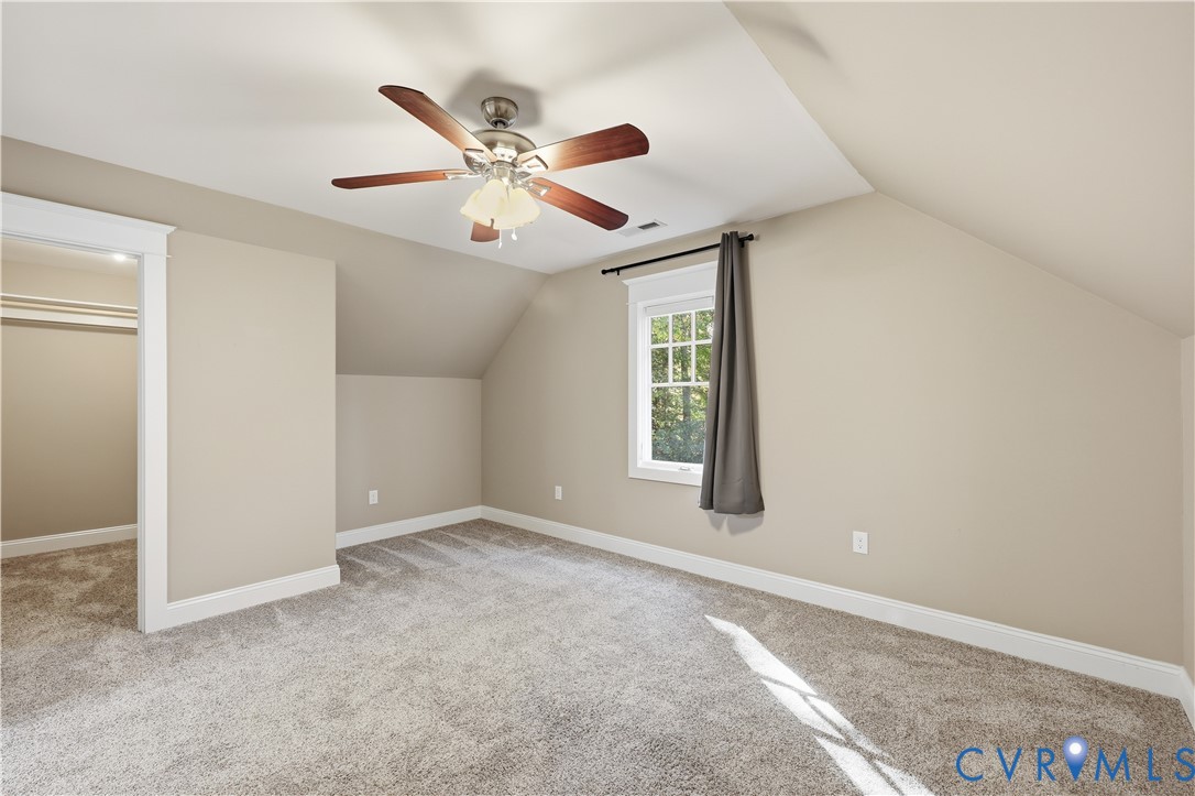 Upstairs Bedroom Room featuring sloped ceilings, wall-to-wall carpeting, a multi-blade ceiling fan with integrated lighting, and a single-hung window with decorative muntins
