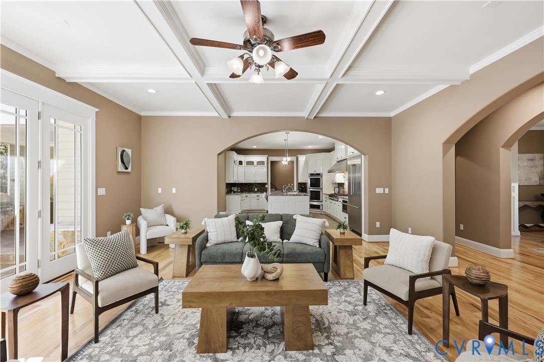 Coffered ceiling, wood-finish flooring, recessed lighting, ceiling fan with integrated light fixture, and arched doorways