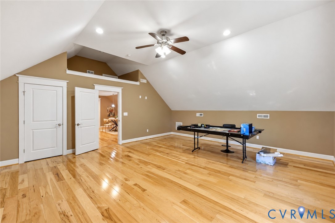 Vaulted ceilings, wood-finish flooring, recessed lighting, and a multi-blade ceiling fan