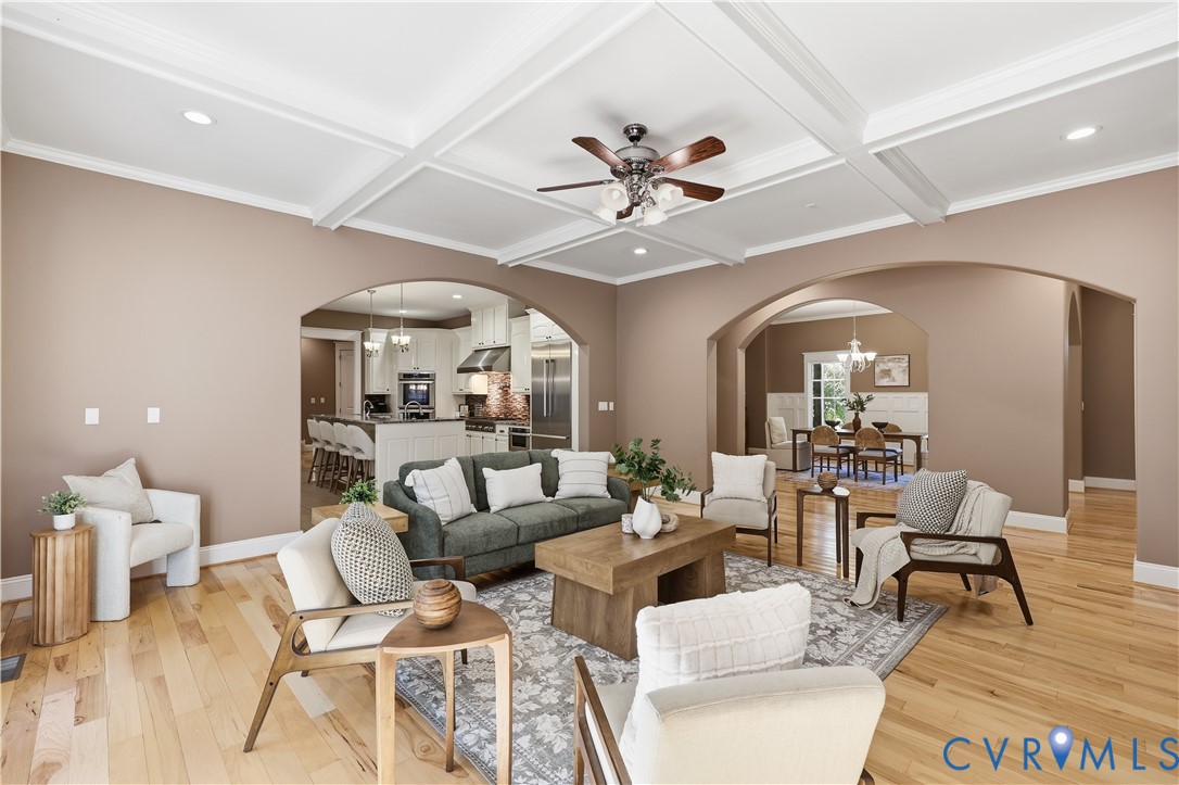 Coffered ceiling with integrated recessed lighting, wood-finish flooring, and multiple wide arched entryways