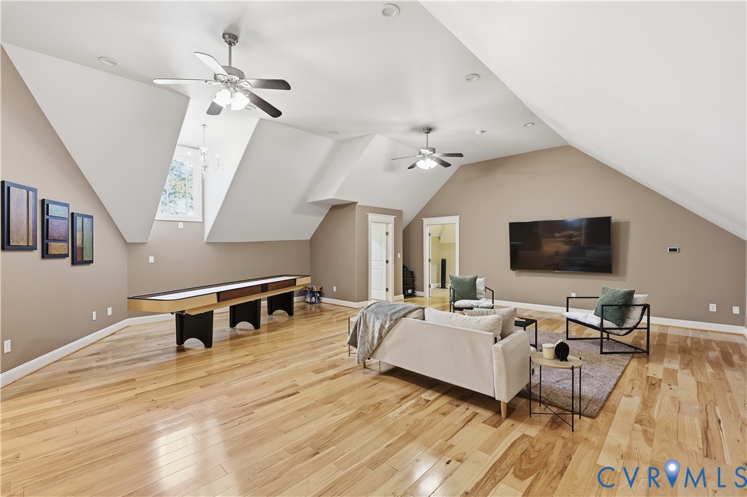 Vaulted ceilings with dormer windows, wood-finish flooring, and dual ceiling fans