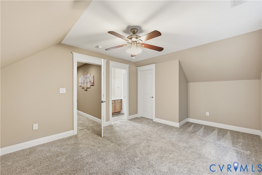Upstairs Bedroom, Neutral interior space featuring carpeted flooring, vaulted ceilings, and a ceiling fan with integrated light fixture
